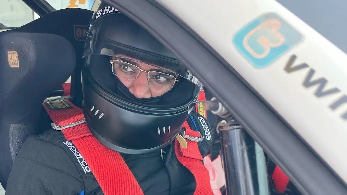Udi wearing a racing helmet inside a Volkswagen Polo Cup car